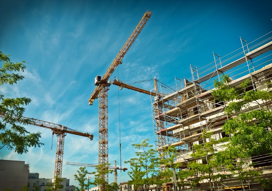 Abbildung Rohbau eines Gebäudes mit Baukränen